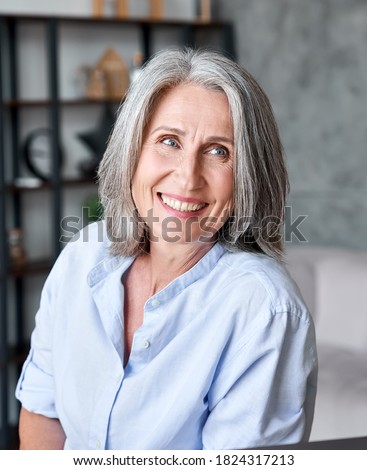 Happy beautiful elegant old adult business woman smiling looking away in office. Positive stylish classy grey-haired middle aged mature female teacher, manager, entrepreneur or coach portrait. Royalty-Free Stock Photo #1824317213
