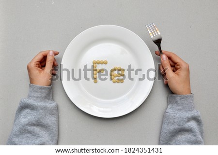 Sign of the trace element "iron" from tablets on a white plate. Iron deficiency in the body Royalty-Free Stock Photo #1824351431