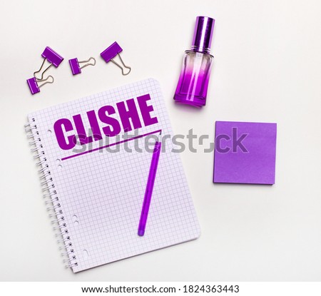 On a light background - a lilac gift, perfume, lilac business accessories and a notebook with the inscription CLICHE. Flat lay. Female business concept