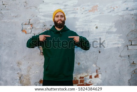 City portrait of handsome hipster guy with beard wearing green (watercolor) blank hoodie with space for your logo or design. Mockup for print Royalty-Free Stock Photo #1824384629