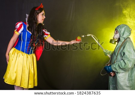 Woman dressed as fairytale character holds Radioactive atomic nuclear ionizing radiation danger warning symbol on apple. Nuclear and radiation measurement concept.