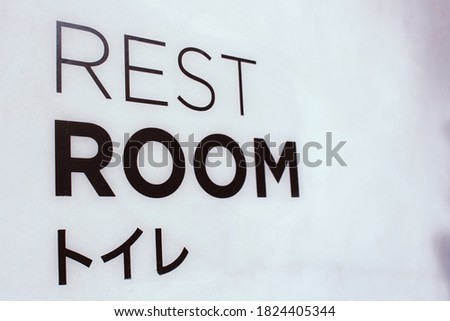 The words Rest room on the concrete wall with Japanese languages mean rest room