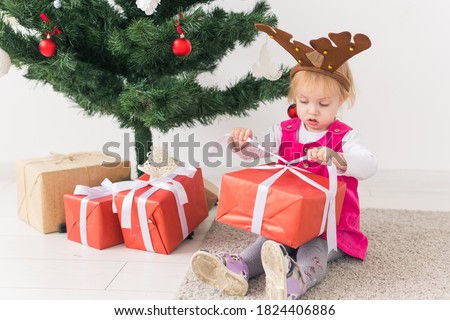 Child holding Christmas gift. Kid having fun at home. Xmas winter holiday concept