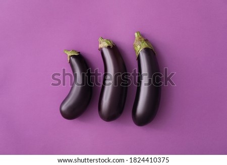 Raw ripe eggplants on purple background, flat lay Royalty-Free Stock Photo #1824410375