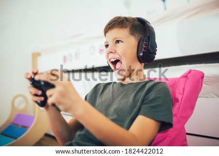 Little boy with gamepad playing video game at home