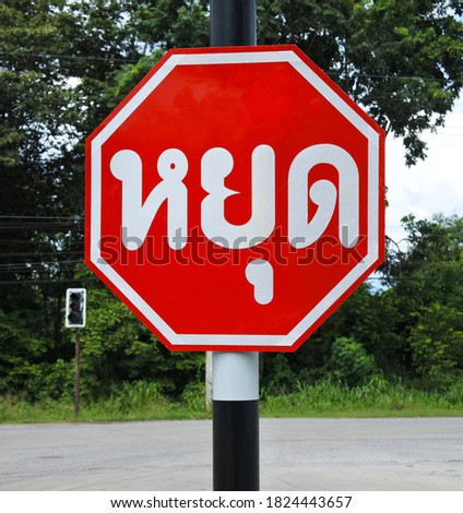 Traffic signs in Thai language alert that all types of vehicles must stop, and when they see it is safe, they can move with caution.