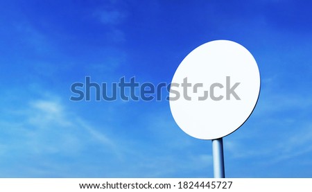 Mockup of a round road sign on a metal pole, against a blue sky