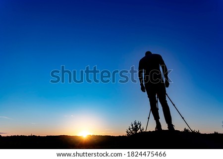 Silhouettes of the landscape photographer on the background of the sunset.