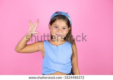 Young beautiful child girl over isolated pink background doing hand symbol