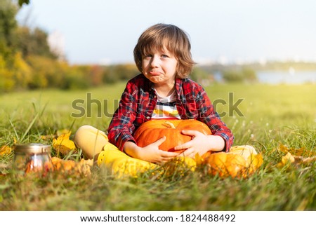 Cute boy play with pumpkin in autumn park on Halloween. Kids trick or treat. Fun in fall. Dressed up child.