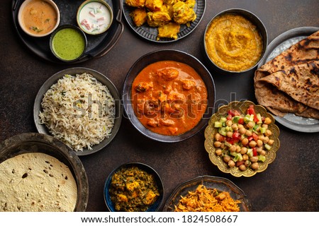Variety of Indian food, different dishes and snacks on dark rustic background. Pilaf, butter chicken curry, rice, palak paneer, chicken tikka, dal soup, naan bread, assortment of chutney. Top view
 Royalty-Free Stock Photo #1824508667