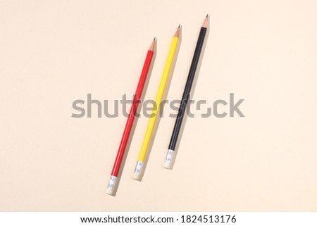 three different colors pencils on a beige paper background with copy space for your text