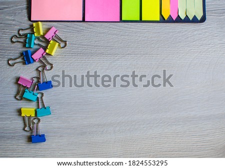 Colorful stickers,colored metal binder clips. Stationery isolated on wooden background. Tool for clamping paper documents. Office metal foldable suspenders. Close up.Copy space