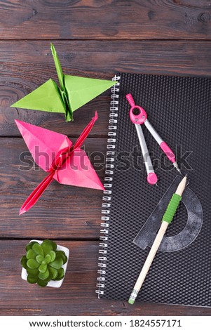 Still life of items for studying. Colorful origami, compass and notebook on the wooden table.