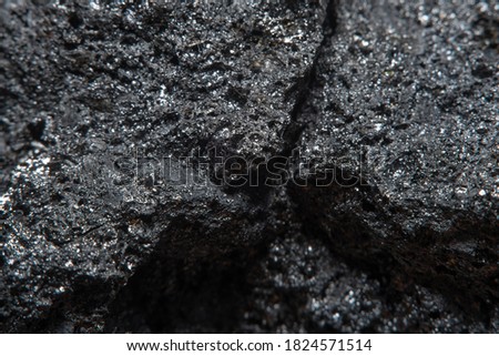 Blurred black background in soft focus with hard coal at high magnification. An image on the theme of geology and the extraction of minerals and natural fuels.