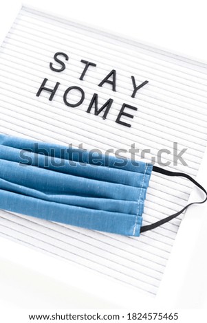 STAY HOME sign on message board with a homemade face mask.