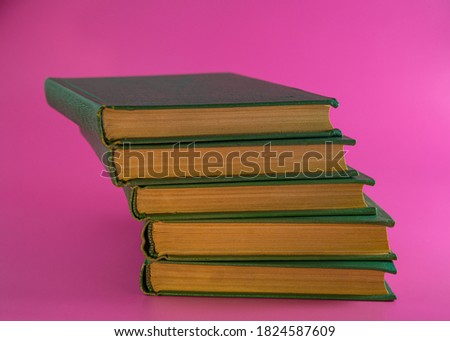 stack of five books in green covers lies on a pink background. For design.