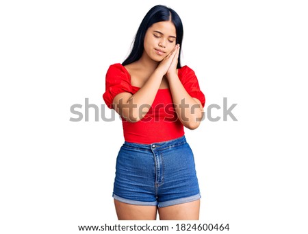 Young beautiful asian woman wearing casual clothes sleeping tired dreaming and posing with hands together while smiling with closed eyes. 