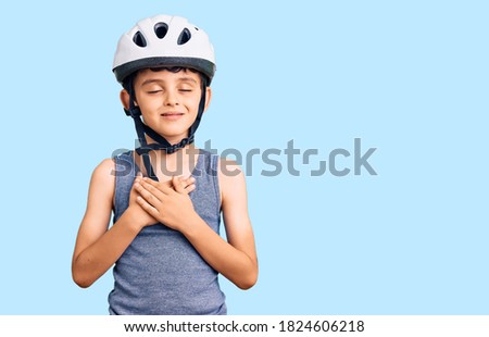 Little cute boy kid wearing bike helmet smiling with hands on chest with closed eyes and grateful gesture on face. health concept. 