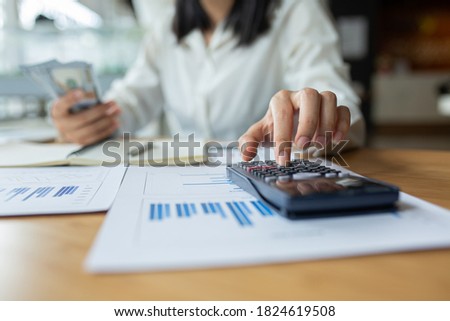 Close up businessWoman Hand doing finances and calculate on desk about cost at home office.Business communication concept