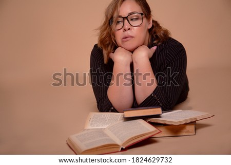 Fat woman in glasses holding books isolated on biege background 