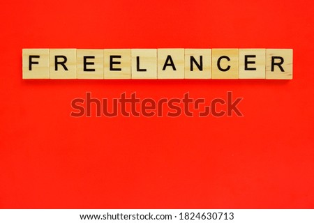 Word freelancer. Top view of wooden blocks with letters on red surface