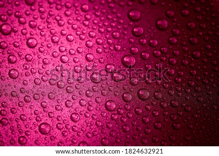 Hot pink water drops on a glitter surface, abstract macro photography