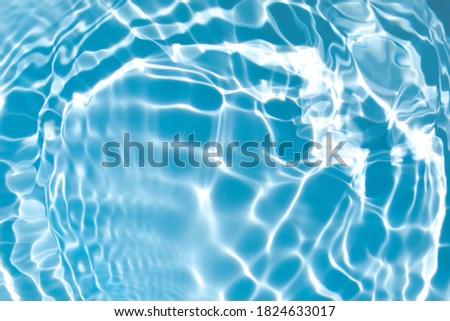 blurred transparent blue colored clear calm water surface texture with splashes and bubbles. Trendy abstract nature background. Water waves in sunlight with copy space.