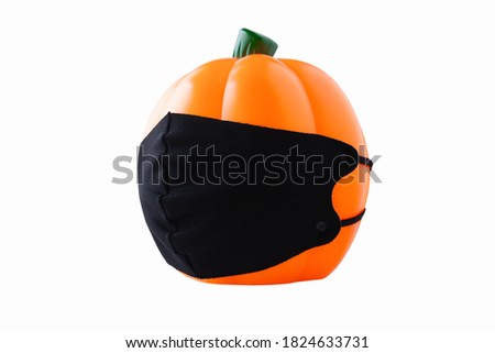 Plastic orange Halloween pumpkin with black face mask, on white background, side view