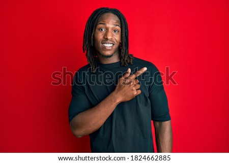 African american man with braids wearing casual clothes smiling cheerful pointing with hand and finger up to the side 
