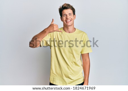 Handsome caucasian man wearing casual clothes smiling doing phone gesture with hand and fingers like talking on the telephone. communicating concepts. 