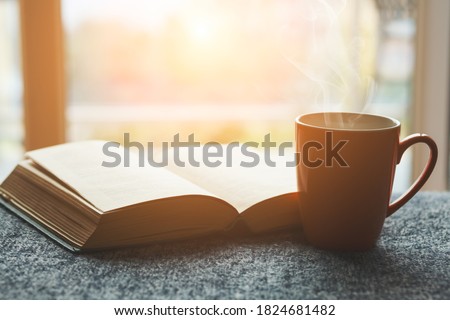 cup of fresh tea or morning coffee and open book at home at morning light, reading book and drinking coffee concept Royalty-Free Stock Photo #1824681482