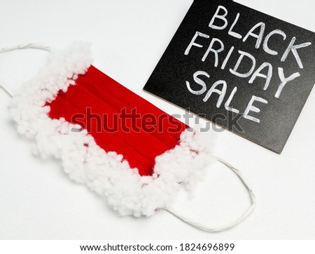 protective mask for Santa Claus, red and white on a white background and black chalk board with chalk lettering "black friday sale"