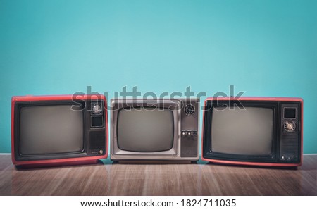 Retro old three TVs receiver on table with gradient aquamarine wall background. Vintage television style