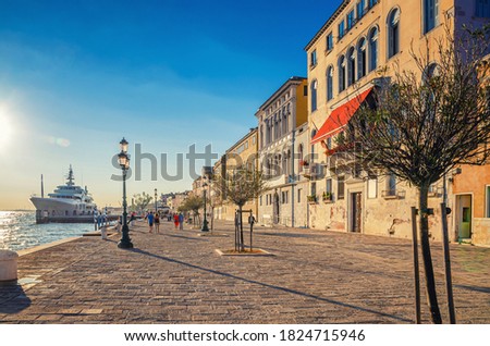 People tourists are walking down embankment promenade Fondamenta Zattere Al Ponte Lungo with trees and yacht moored in water of Giudecca canal waterfront in Venice city historical centre, Italy Royalty-Free Stock Photo #1824715946