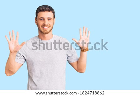 Handsome young man with bear wearing casual tshirt showing and pointing up with fingers number ten while smiling confident and happy. 
