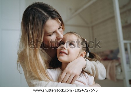 mother hugging and kissing her adorable daugter