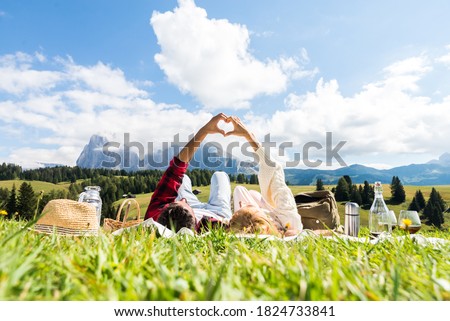 Romantic couple in love doing picnic visiting mountains alps. Boyfriend and girlfriend enjoying love doing heart shape with hands outdoor. Royalty-Free Stock Photo #1824733841