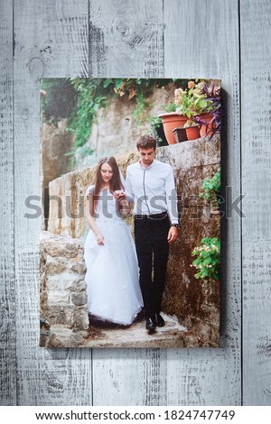 Photo canvas print. Sample of stretched wedding photography, front view. Bridal portrait hanging on grey wooden wall