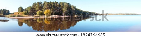 Panoramic view of the forest island, pond or lake. The reflection in the water. Beautiful widescreen autumn landscape. 