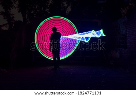 One people standing alone against a incredible blue and red circle light painting as the backdrop