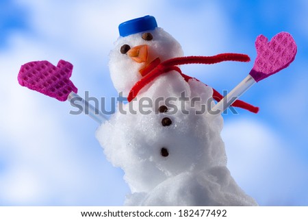 Little happy christmas snowman in blue screw top as hat red scarf and pink gloves outdoor. Winter season seasonal specific. Blue sky background.