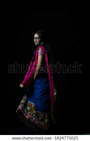 Indian girl in traditional chaniya choli for navratri with a fashionable hairstyle poses in studio on black background. Navratri is an Indian Festival and Chaniya choli its traditional costume