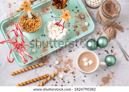 Top View of Hot Cocoa Bar with Christmas Cups and Decorations; Multiple Toppings Pictured; White and Gray Countertop
