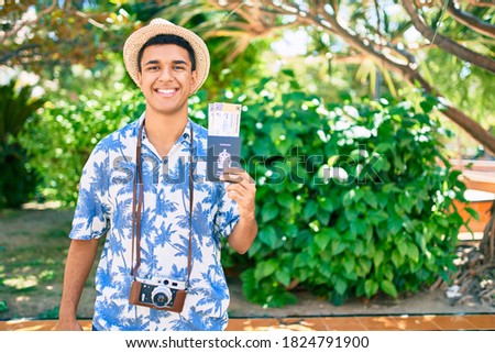 Young arab tourist man using vintage camera holding canadian passport and boarding pass at the park.
