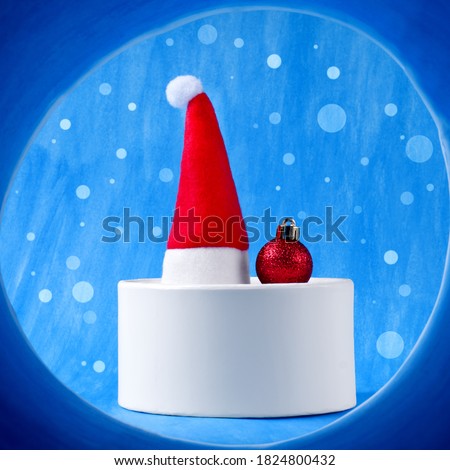 Santa hat and bauble on the white present box against the blue background. View through the spyglass. Concept of Christmas gifts and search for perfect gifts