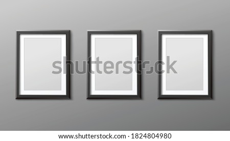 Three photo or picture frames hanging vertically on grey wall, realistic vector mockup illustration isolated on background. Template of blank black frameworks cadre. Royalty-Free Stock Photo #1824804980