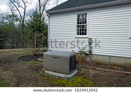 Residential standby generator installed on a concrete pad Royalty-Free Stock Photo #1824812042