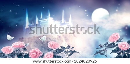 Fantasy fairytale photo background of beautiful fairy pink rose flower garden and butterflies, magical castle in blue night sky, shining stars and glowing moon. Idyllic tranquil fabulous mystic scene.