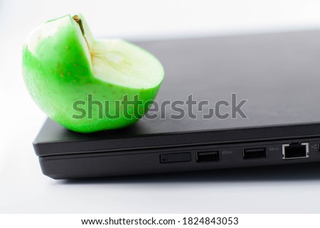 Nice green apple on a black computer and on white background
